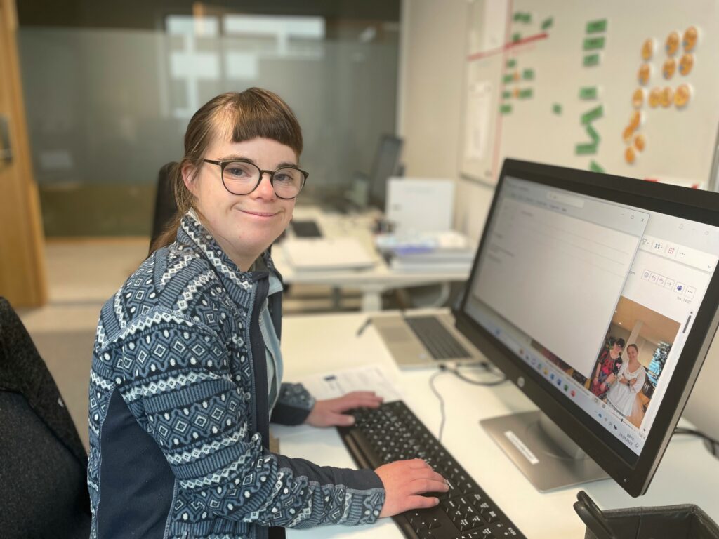 Kvinne med Downs syndrom som sitter foran PC